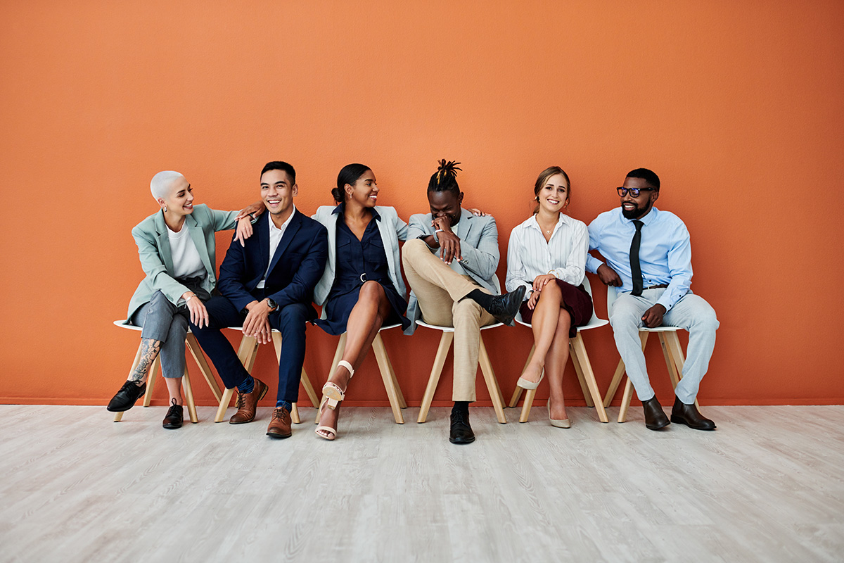 Web design agency concept - group of young professionals in front of an orange wall.