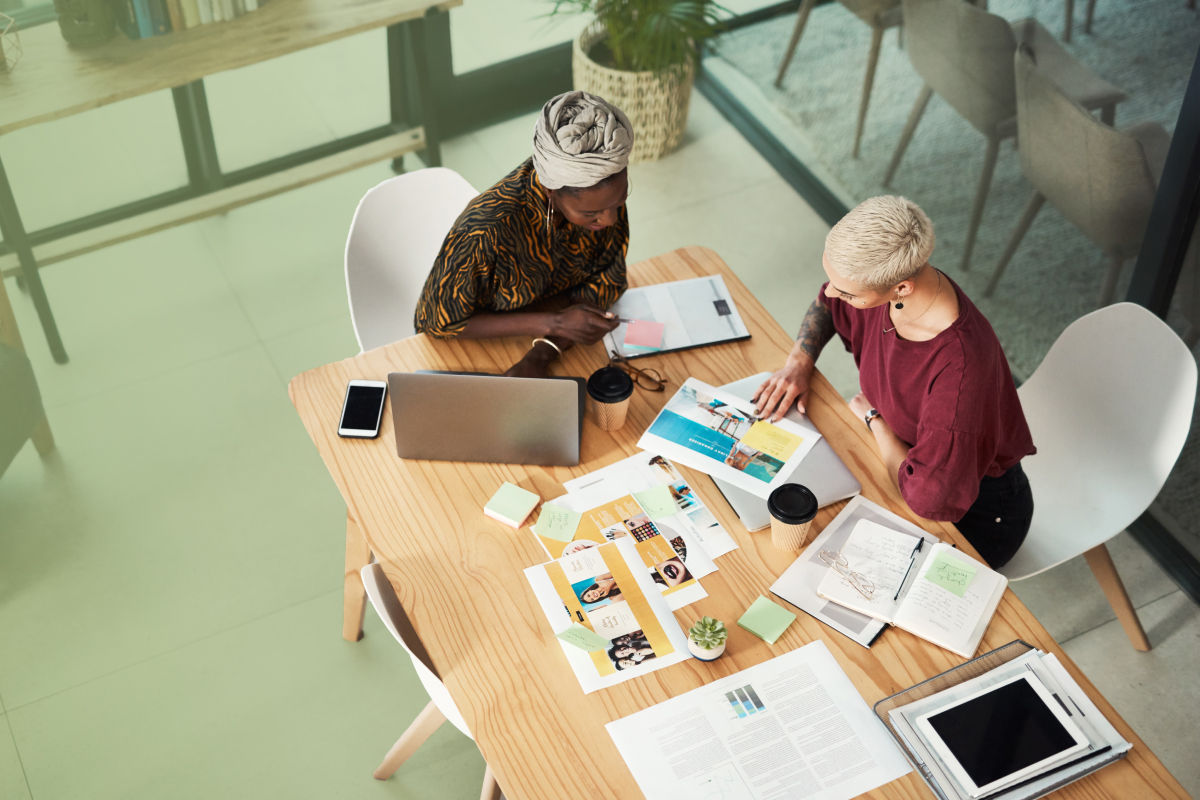 Two workers considering the top reasons for a website redesign around a table.