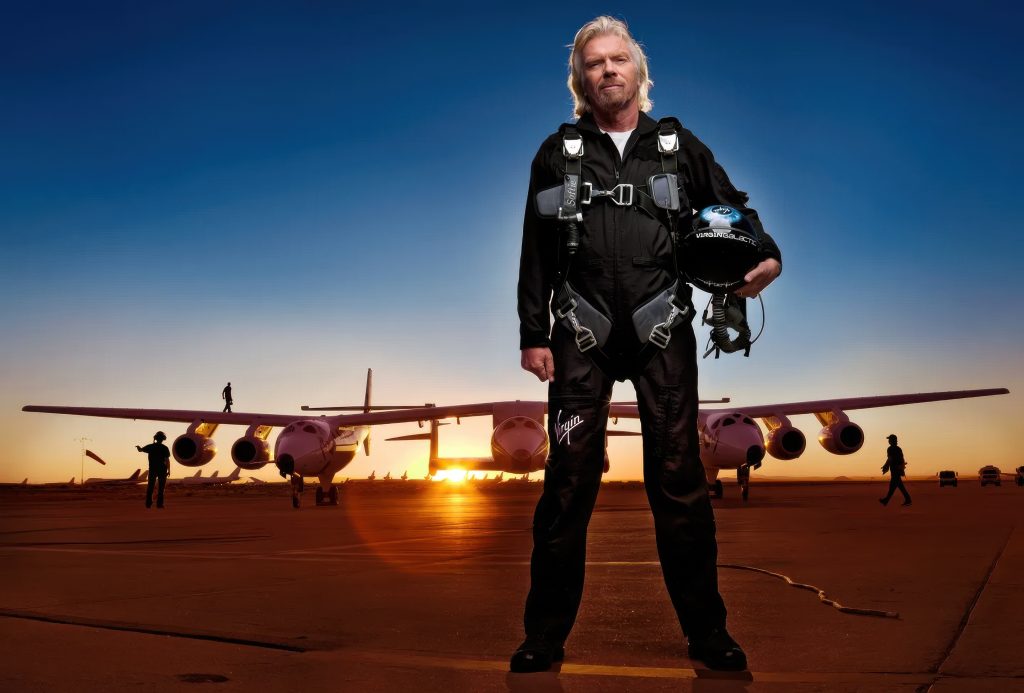 Virgin Group’s Richard Branson stands on a tarmac in front of three experimental airplanes.